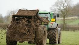 Tractor spreading farmyard manure on grassland